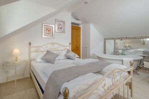 Ein Schlafzimmer mit Bett, Nachttisch, Lampe und einem großen Spiegel.
