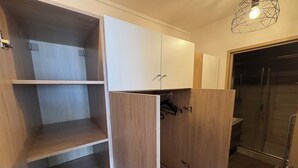 A room with wooden cabinets, a shower area, and a hanging light fixture. - Urban cocoon with panoramic view - Balcony - Fully equipped (Saint-Étienne)