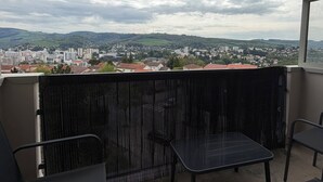 A balcony with a view of a cityscape, including buildings and hills. - Urban cocoon with panoramic view - Balcony - Fully equipped (Saint-Étienne)