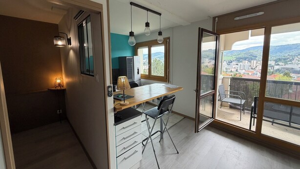 A modern apartment with a balcony, a dining area, and a view of the city. - Urban cocoon with panoramic view - Balcony - Fully equipped (Saint-Étienne)