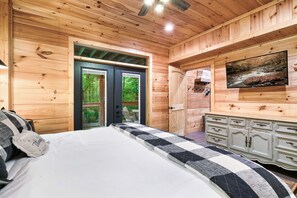 Ein Schlafzimmer einer Holzhütte mit Bett, Kommode und Fernseher.