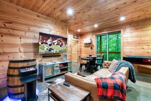 A wooden cabin interior with a television, wooden barrel, and a cozy seating area. - Luxe Craftsman | 3 King Suites | Fire Pit | Top 5% (Gatlinburg)
