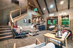 Un interior rústico con una escalera, muebles de madera, un comedor y vistas por una ventana.