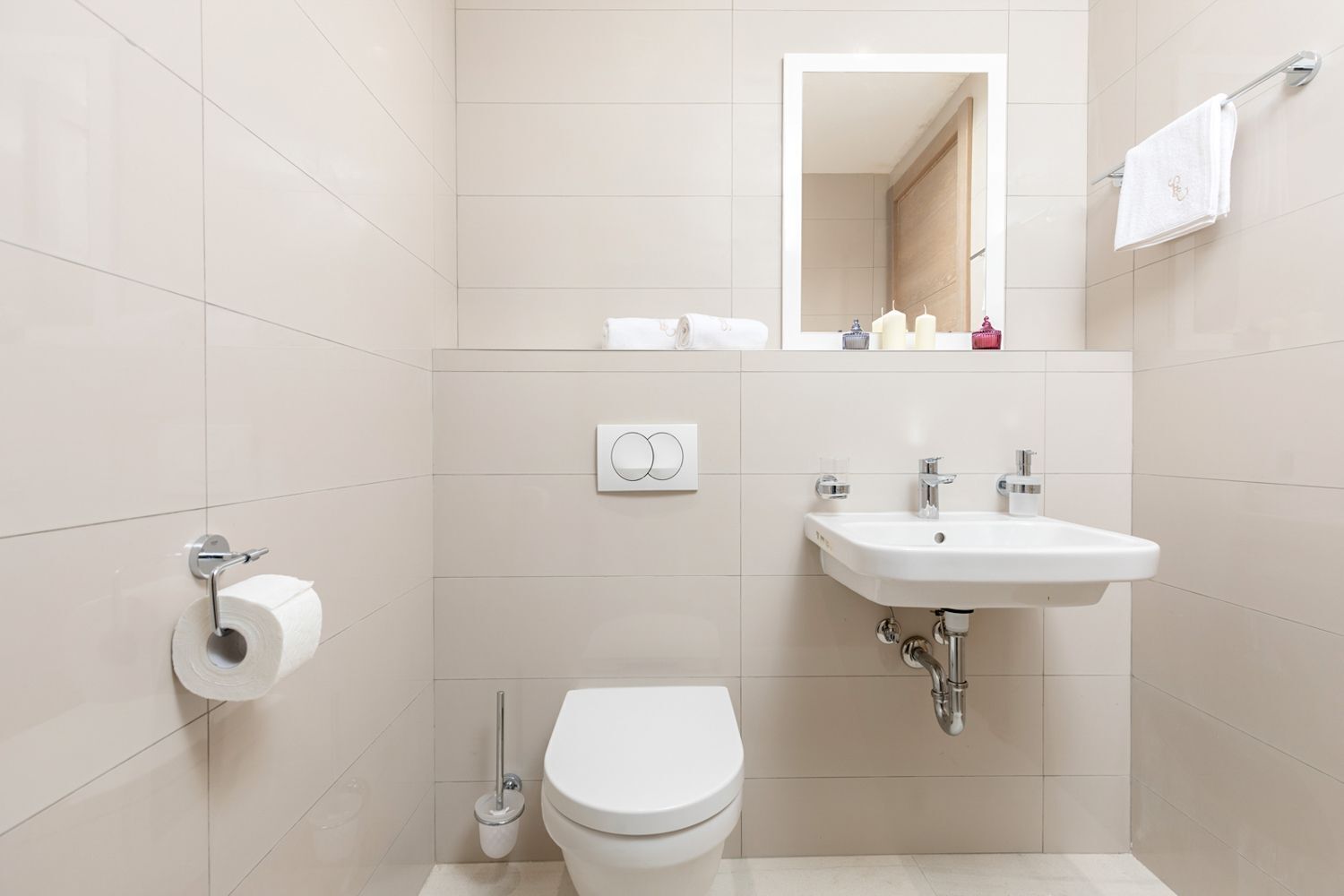 Un baño moderno con inodoro, lavabo, espejo y toallero.
