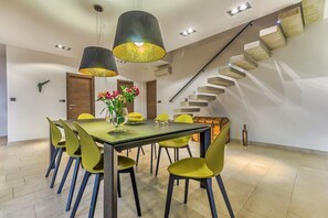 Ein Essbereich mit Tisch und Stühlen, einer Vase mit Blumen sowie einer Treppe mit markantem Design.