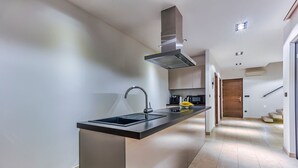 Ett modernt kök med en central köksö, apparater i rostfritt stål och en stilren design.