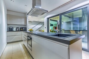 Eine moderne Küche mit einer zentralen Kochinsel, eingebauten Geräten und einem großen Fenster.
