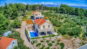 Ein zweistöckiges Haus mit Swimmingpool, umgeben von Bäumen und einer Berglandschaft.