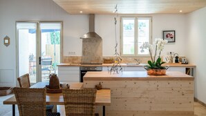 Eine moderne Küche mit Holzboden, einer zentralen Kochinsel und einem Essbereich mit Korbmöbeln.