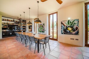 Cozinha ampla com área de refeições, janelas grandes e estante de livros.
