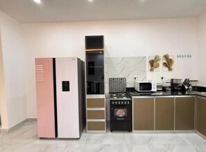 Una cocina moderna con refrigerador, microondas, estufa y alacenas.
