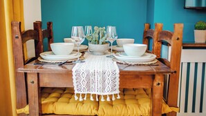 Una mesa de comedor puesta con cuencos blancos, copas de vino y una planta en maceta.