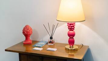 Una mesita de noche de madera con una lámpara, un objeto decorativo, un libro y un pequeño recipiente.