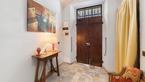 A hallway with a wooden door, a table with a lamp, and a chair. - Room 'Perla' with Shared Terrace, Wi-Fi and Air Conditioning (Casalnoceto)