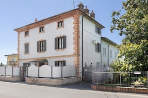 Ein zweistöckiges Gebäude mit weißer Fassade und roten Backstein-Akzenten, inklusive eines einkehren und einem sichtbaren Balkon.