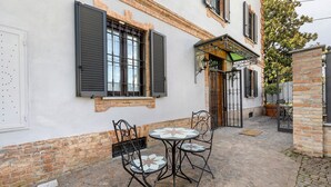 A courtyard with a table and chairs, a brick wall, and a gate. - Room 'Perla' with Shared Terrace, Wi-Fi and Air Conditioning (Casalnoceto)