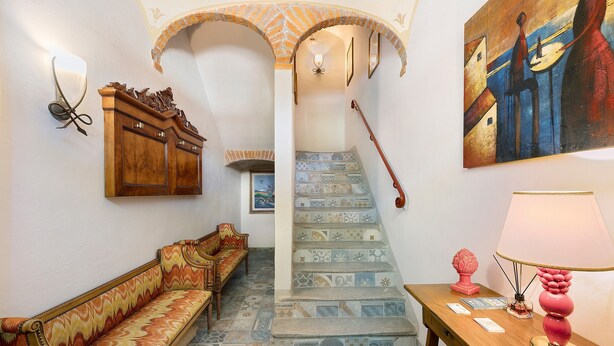 A staircase with patterned tiles, a wooden bench, a table with a lamp, and a painting on the wall. - Room 'Perla' with Shared Terrace, Wi-Fi and Air Conditioning (Casalnoceto)
