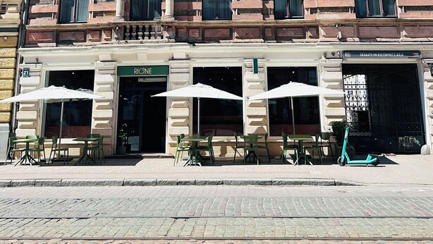 A multi-story building with a ground-floor restaurant featuring outdoor seating. - Stylish apartment with AC in the heart of Riga Centre (Riga)
