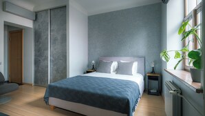 A modern bedroom with a bed, bedside tables, a radiator, and a window with a plant. - Stylish apartment with AC in the heart of Riga Centre (Riga)