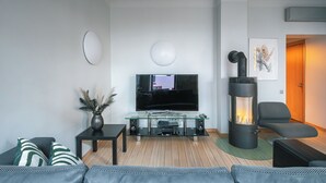 A modern living room with a flat-screen TV, a glass coffee table, a sofa, a black fireplace, and a door leading to another room. - Stylish apartment with AC in the heart of Riga Centre (Riga)