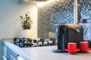 A kitchen with a coffee maker, two red cups, and a potted plant. - Stylish apartment with AC in the heart of Riga Centre (Riga)