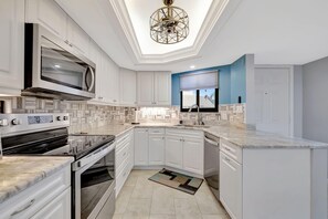 A modern kitchen with white cabinetry, a built-in microwave, a stove, and a dishwasher. - Ocean Village 2 bd 2 bath w loft, walk to beach, pools, golf. Fully furnished. (Fort Pierce)