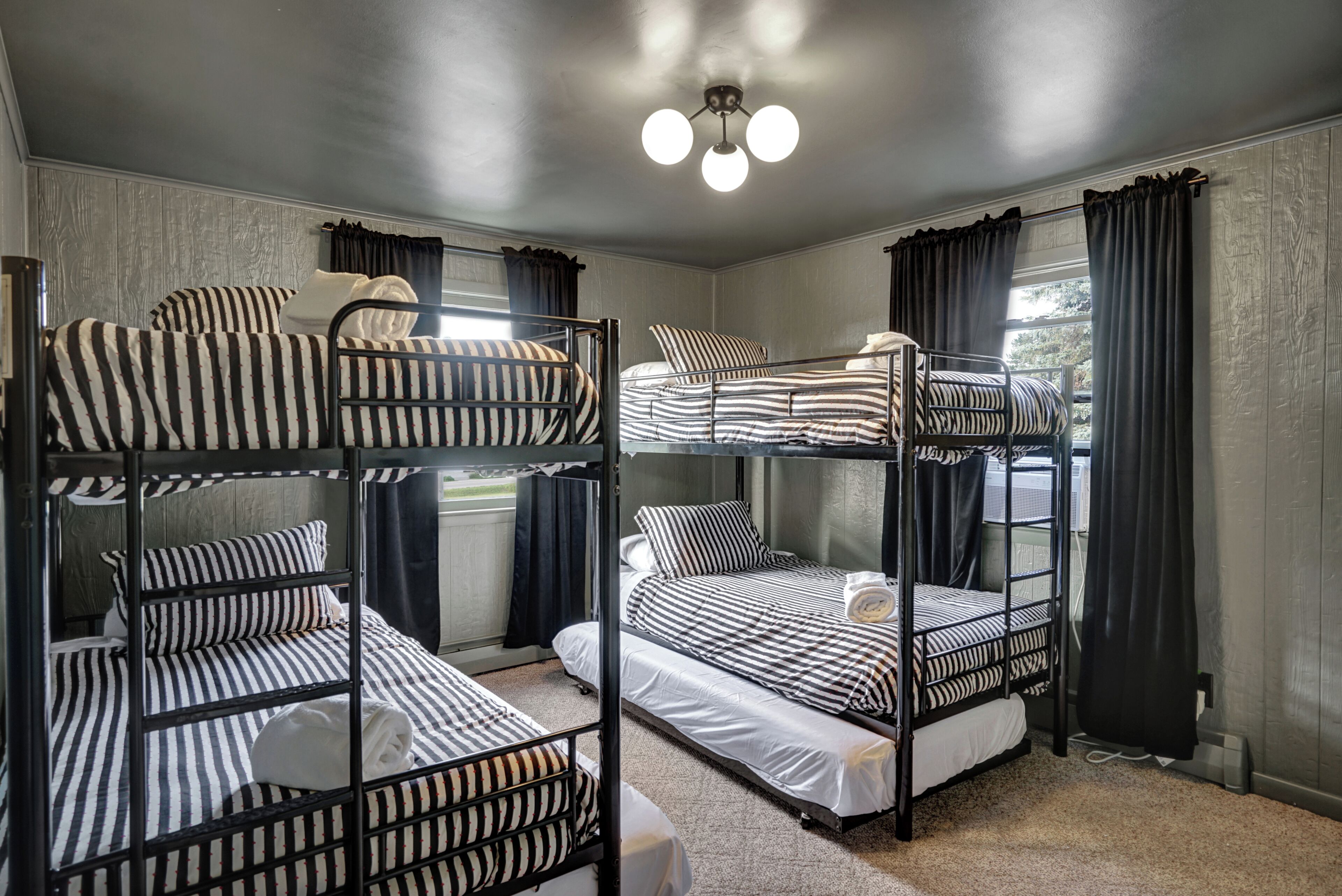 A room with bunk beds, a ceiling light, and a window with curtains.