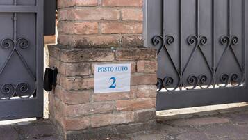 A brick pillar with a sign reading 'POSTO AUTO 2' and a metal gate.