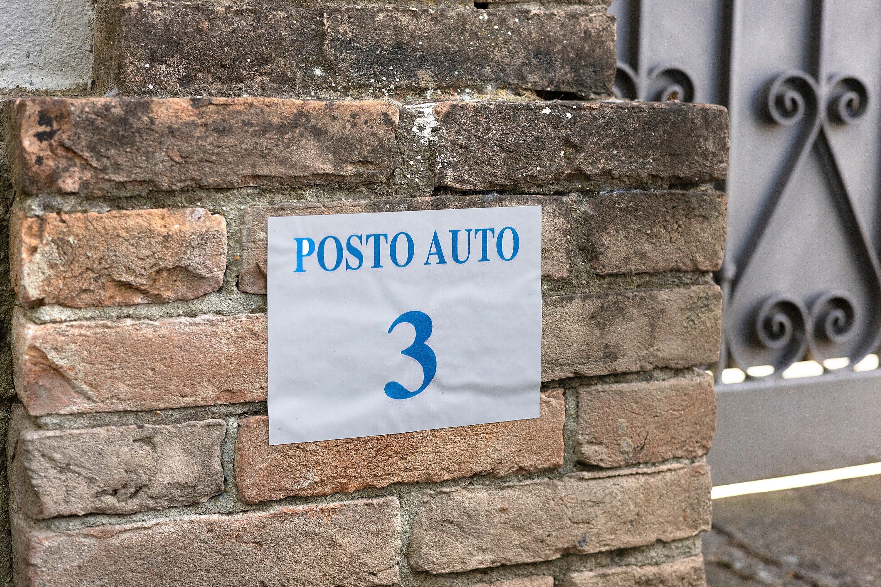 A sign on a brick wall with the text 'POSTO AUTO 3'.