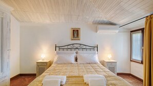 Ein Hotelzimmer mit einem Bett, zwei Nachttischen, einem Fenster mit Vorhängen und einem Deckenventilator.
