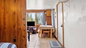 Ein Holzinterieur mit einem Esstisch, einem Fernseher und Blick ins Freie.