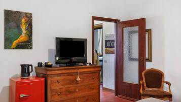 A room with a television, a red filing cabinet, a wooden dresser, a brown chair, and a painting on the wall.
