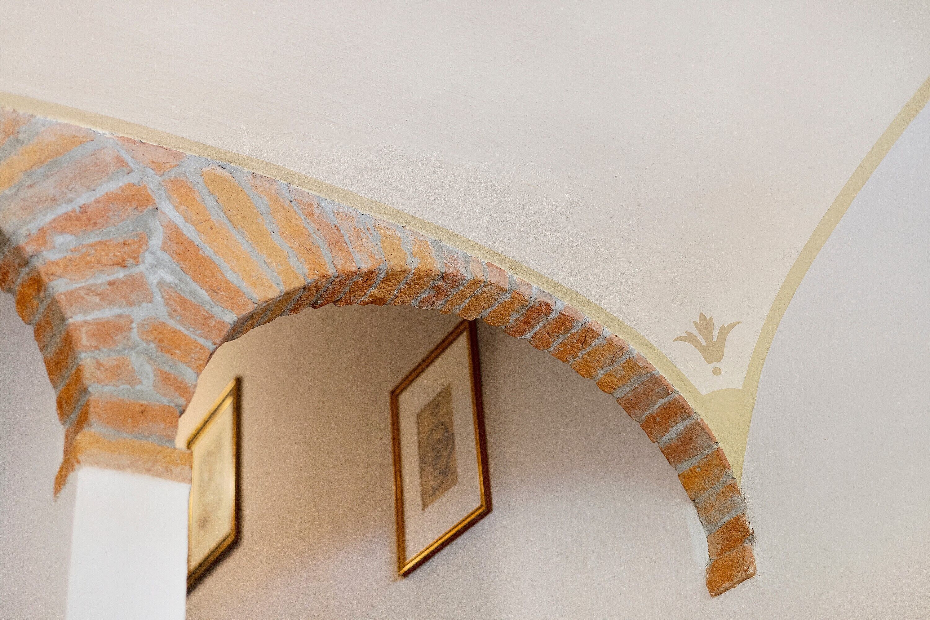 A brick archway with framed pictures on the wall.