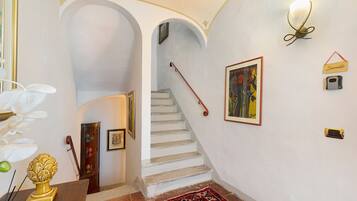 Un escalier aux murs blancs, un tapis rouge et un tableau encadré.