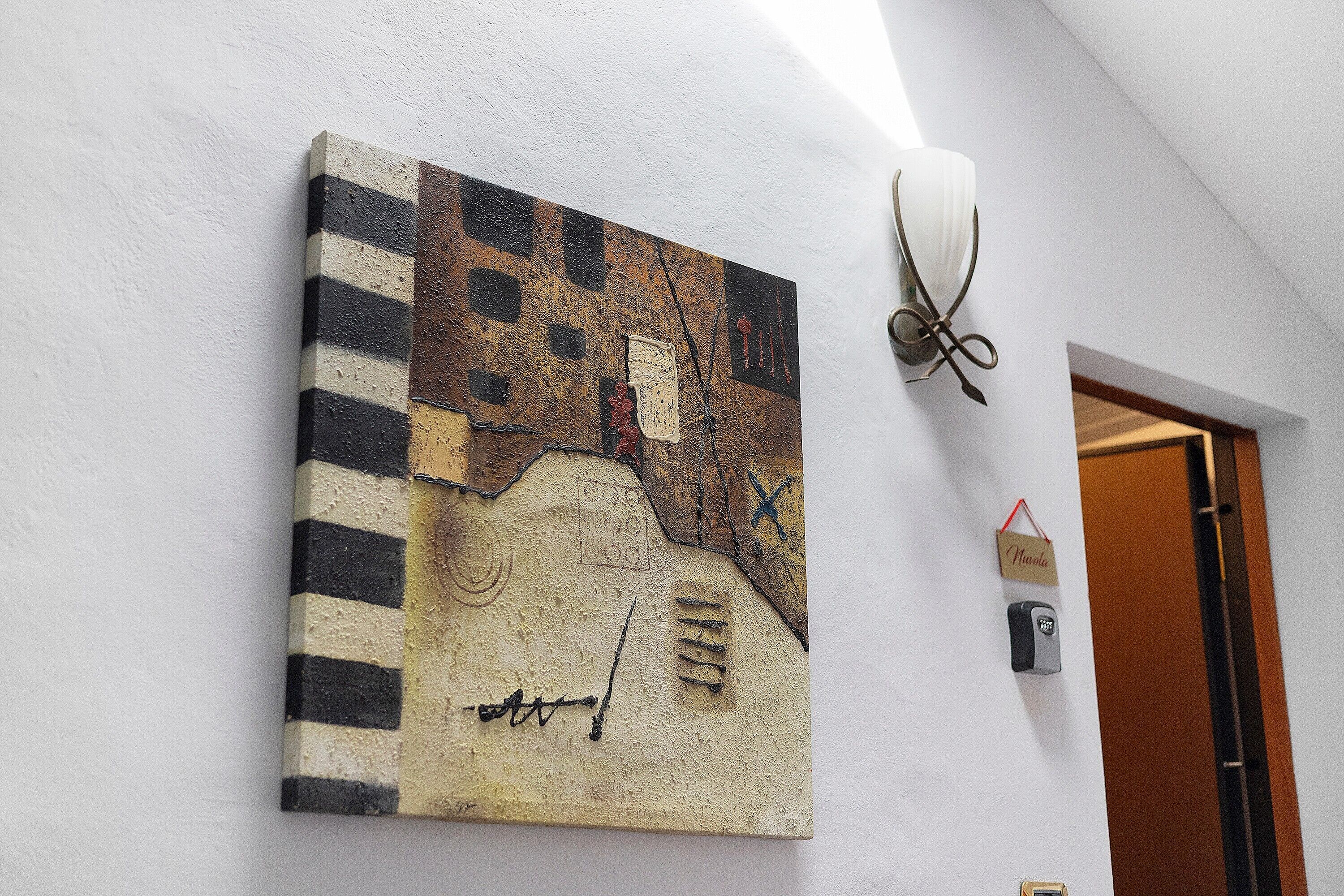 A textured wall art with abstract patterns, a wall-mounted light fixture, and a door with a sign.