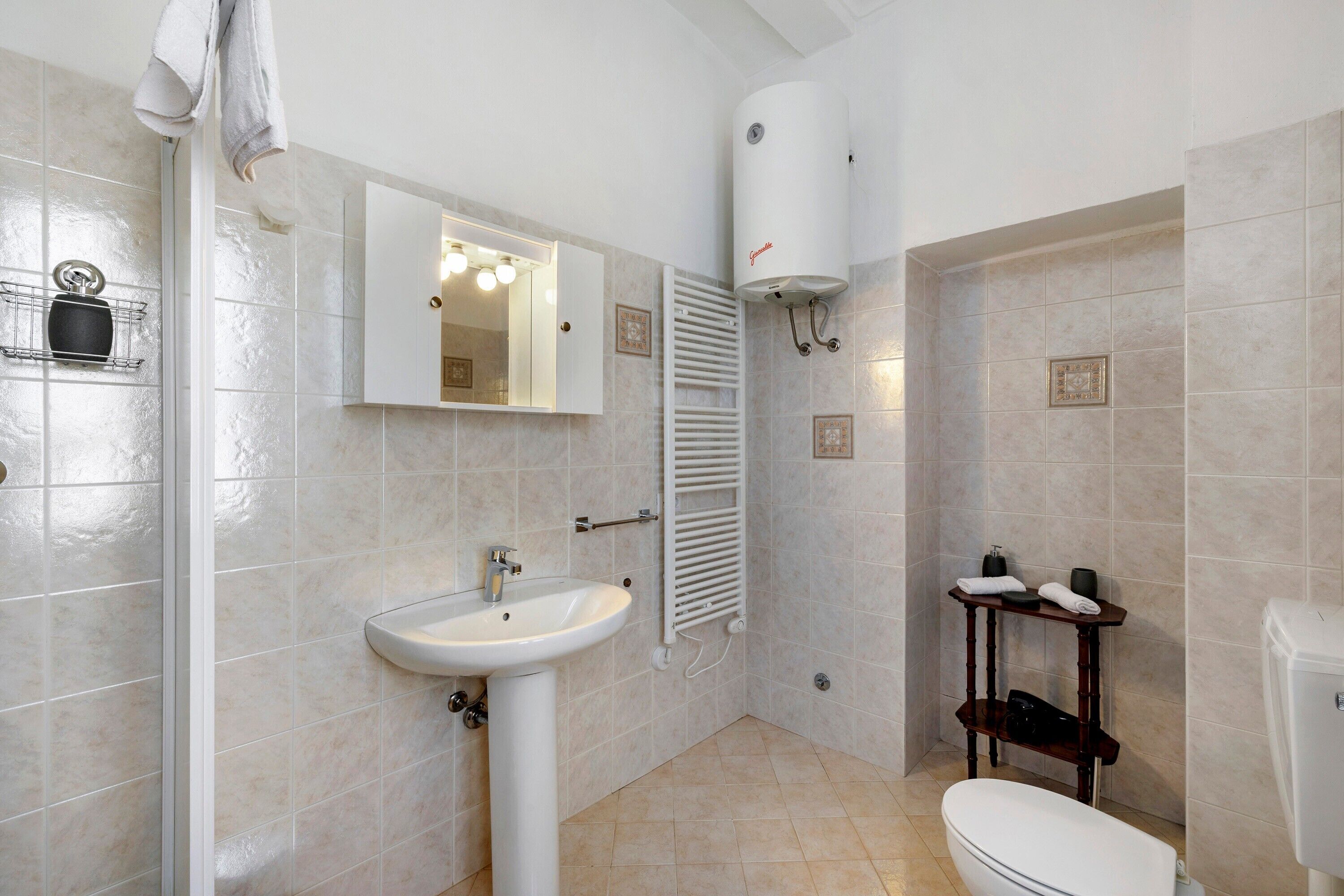 Une salle de bain équipée d’un lavabo, d’un miroir, d’un porte-serviettes, d’un radiateur et de toilettes.