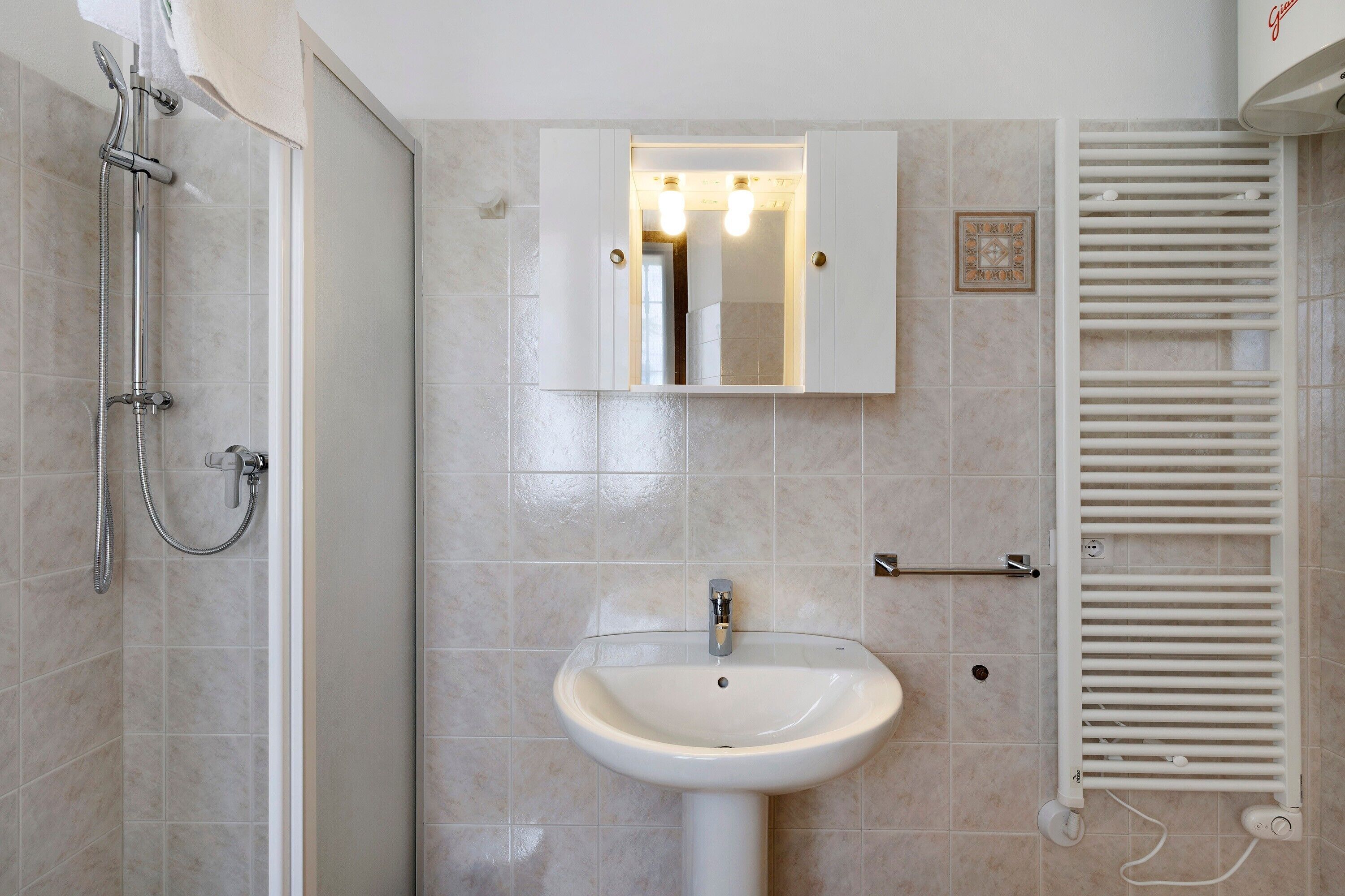 A bathroom with a shower, a sink, a mirror, and a towel rack.