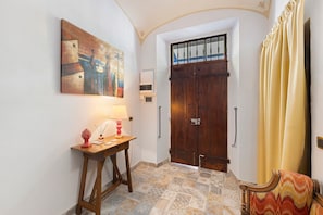 A hallway with a wooden door, a table with a lamp, and a chair.