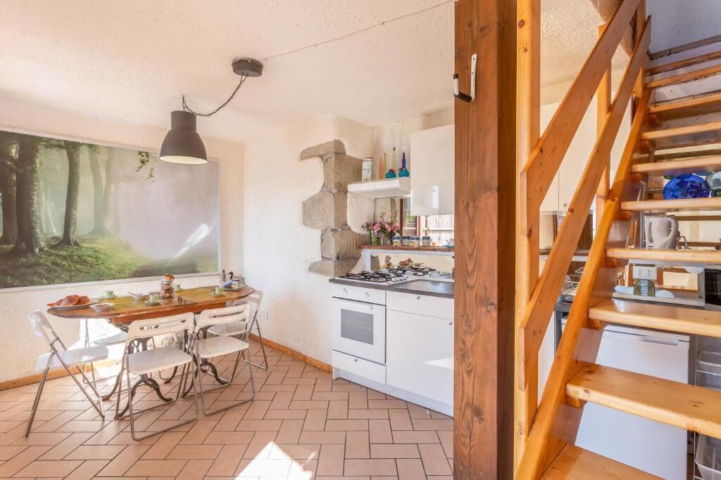 A kitchen with white cabinets, a gas stove, and a wooden staircase.