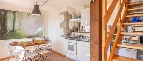 A kitchen with white cabinets, a gas stove, and a wooden staircase.