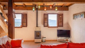 Una habitación acogedora con chimenea, vigas de madera, televisor y sofá.