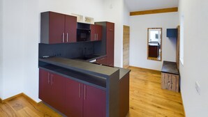 Een moderne keuken met rode kastjes, een zwart aanrecht en een houten vloer.