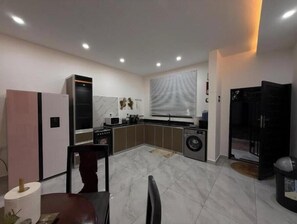 Eine kleine Küche mit Kühlschrank, Mikrowelle, Spüle und Waschmaschine.