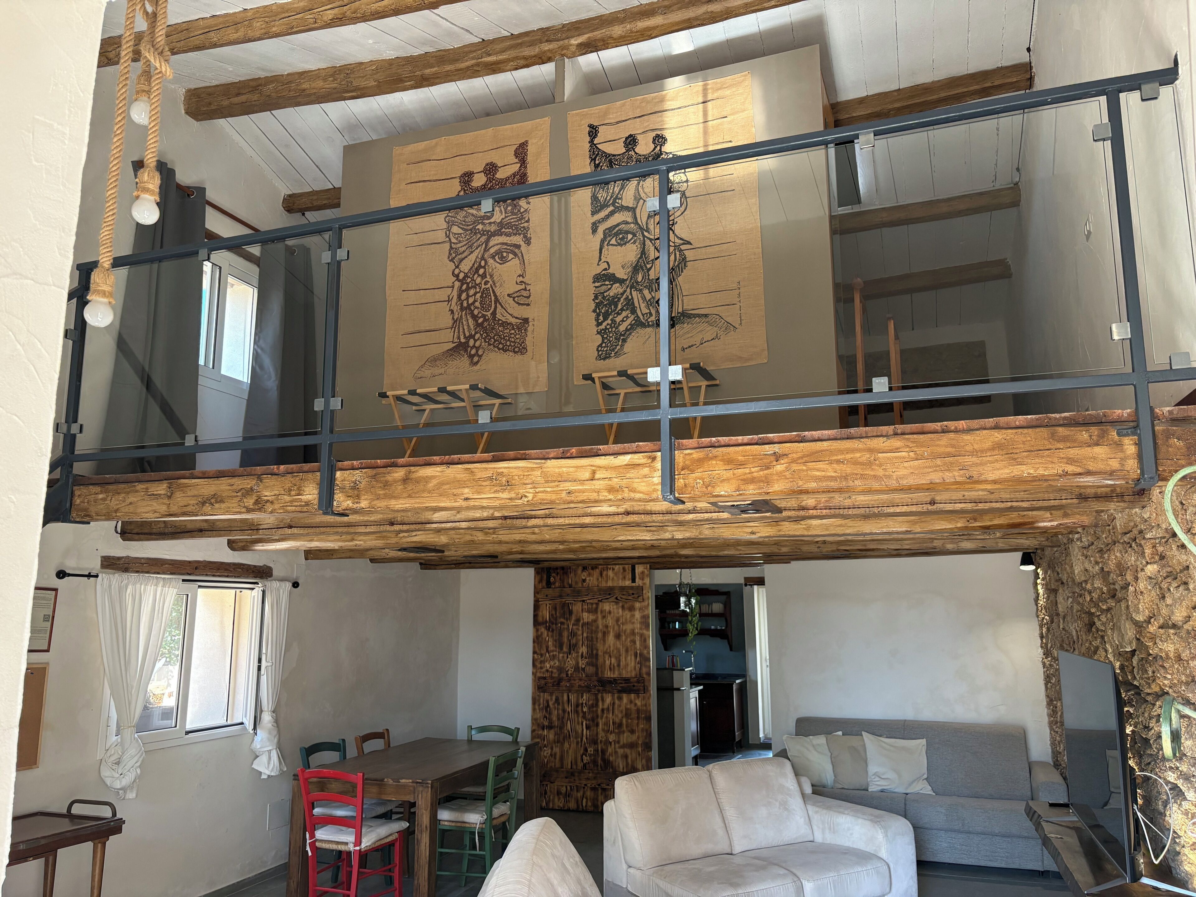 A loft-style room with exposed wooden beams, a dining area, and a sofa.