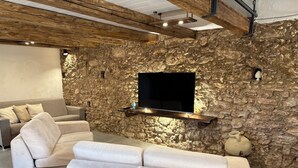 Una sala de estar moderna con una pared de piedra, un televisor montado, un sofá y una mesa de centro.