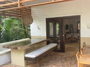 An outdoor dining area with a wooden bench, a table, and a hanging light fixture. - Finca La Verbena - The Sound of Nature (San Jerónimo)