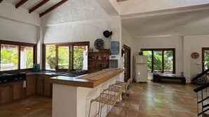 A spacious kitchen with a central island, large windows, and exposed wooden beams. - Finca La Verbena - The Sound of Nature (San Jerónimo)