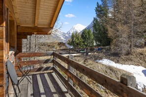 Une cabane en bois dotée d’un balcon donnant sur un paysage montagneux enneigé.