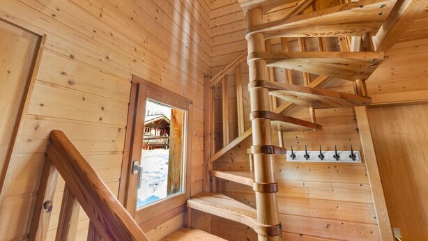 Una escalera de caracol en un interior de madera con vistas al exterior.