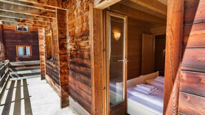 Una cabaña de madera con un vidrio que da a un dormitorio con una cama y una mesita de noche.
